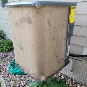 An extremely dirty outdoor AC condenser unit requiring cleaning by Trade Allies Heating and Cooling in Ankeny, IA.