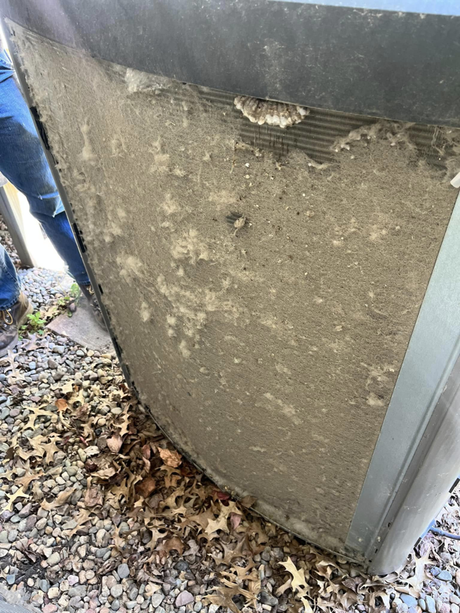 A heavily soiled outdoor air conditioning unit coil covered in dirt and debris, before cleaning by Four Season Heating & Cooling in Saint Joseph, MO.