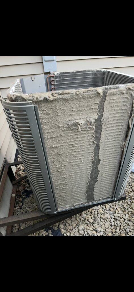 A very dirty outdoor air conditioning unit with coils covered in debris, showing a need for service by Holzer Heating And Cooling in Savage, MN