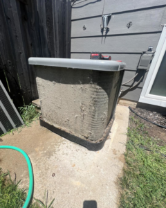 A heavily soiled outdoor AC condenser unit needing cleaning service from Noble Heating And Cooling in Wichita, KS.