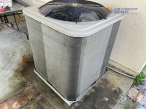 A dirty outdoor HVAC condenser unit, showing a need for cleaning or maintenance from Air Comfort Experts in Pasadena, CA.