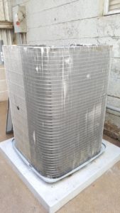 A dirty outdoor HVAC condenser unit in need of cleaning or maintenance by ALL YEAR Heating, Air and Solar in Sacramento, CA.