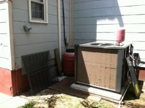 A dirty outdoor HVAC condenser unit with panels removed, indicating service or repair by R A Styron Heating & Air Conditioning, Inc. in Chesapeake, VA.
