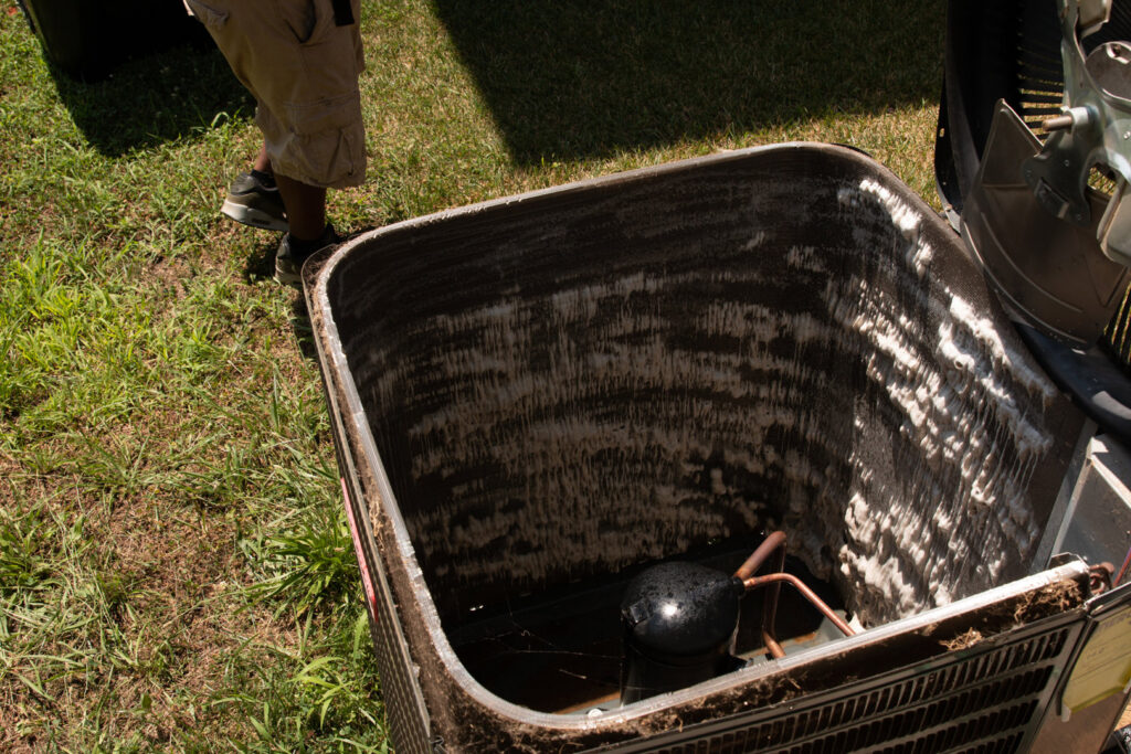 A dirty outdoor HVAC unit with its top removed, showing coils and compressor, ready for service by Nashville Solutions in Nashville, TN