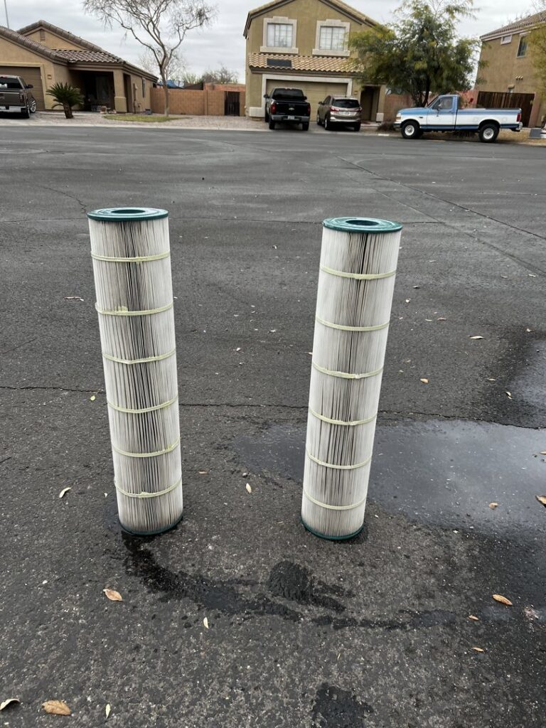 Two dirty pool filters standing on pavement, ready for cleaning or replacement by Edward's Pool Service, LLC in Gilbert, AZ.
