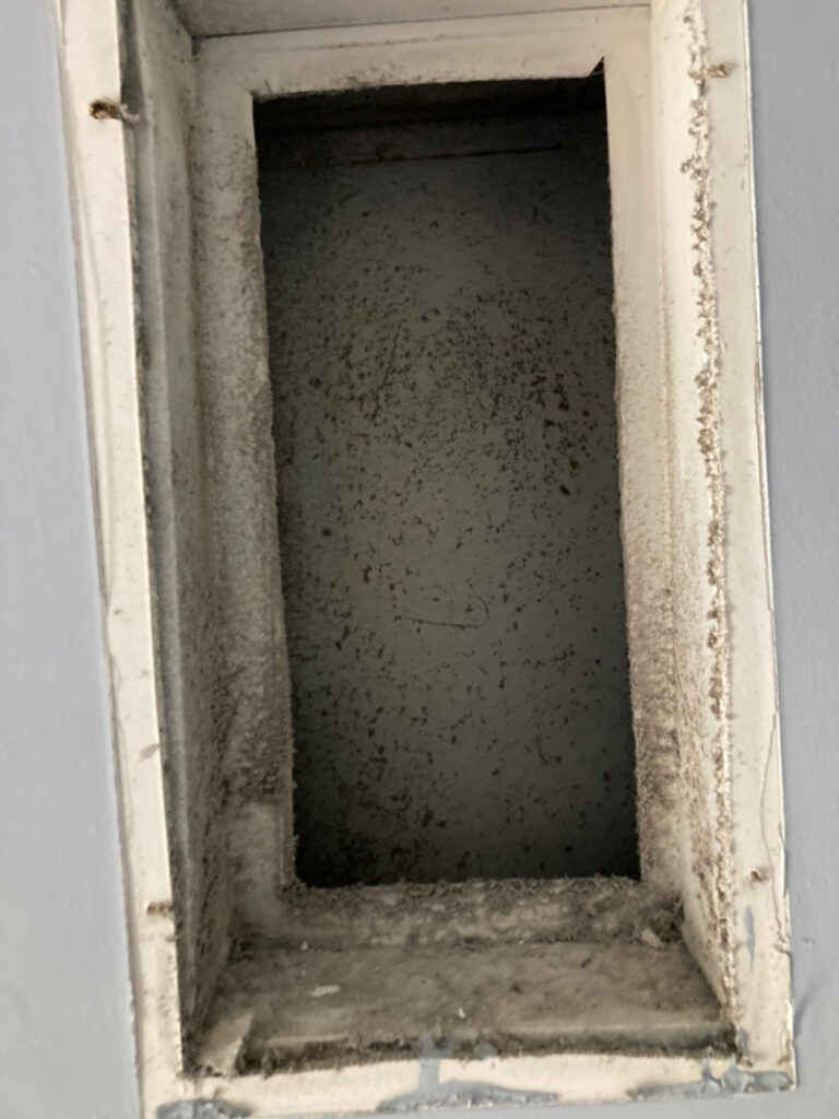 A dirty rectangular air vent opening, showing significant dust and debris accumulation, cleaned by Star Quality Air Duct Cleaning in Silver Spring, MD.