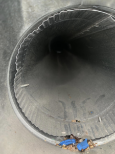A close-up view inside a dirty round air duct before cleaning by Air Duct Solutions in Waukee, IA.