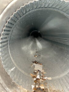 Interior view of a dirty round metal air duct with debris, indicating a need for cleaning by DUCTZ of Siouxland in Vermillion, SD.