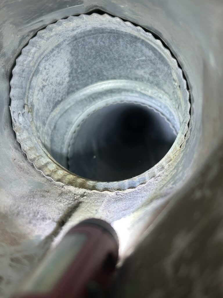 A view inside a dirty round metal air duct with accumulated dust, before cleaning by Vacman Air Duct Cleaning in South Bend, IN