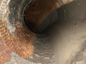 A close-up view of a dirty and rusty air duct interior, showing the need for HVAC cleaning by Craig Baird in Albuquerque, NM.