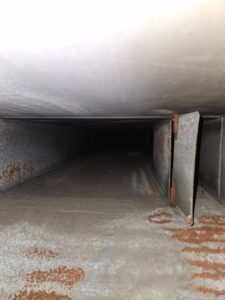 An interior view of a dirty and rusty air duct, highlighting the need for cleaning services from Pro Power Air Duct & Dryer Vent Cleaning in Kenosha, WI.