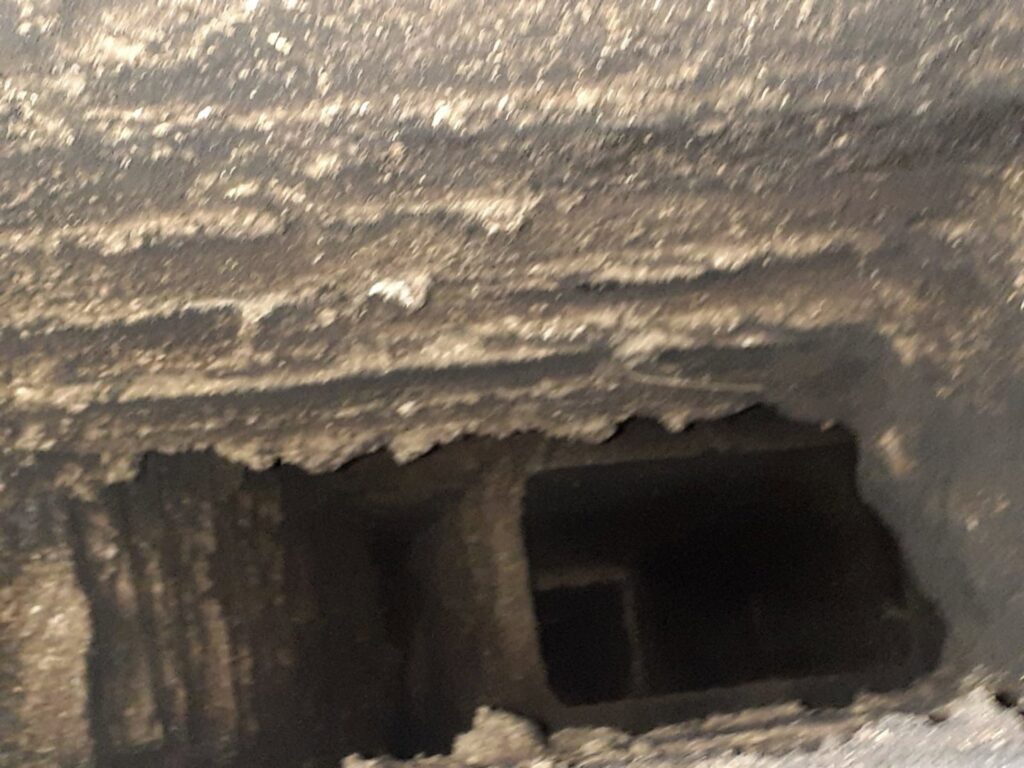 An interior view of a very dirty and sooty chimney flue, highlighting the need for a professional chimney sweep from Colombus Chimney in Elizabeth, NJ.