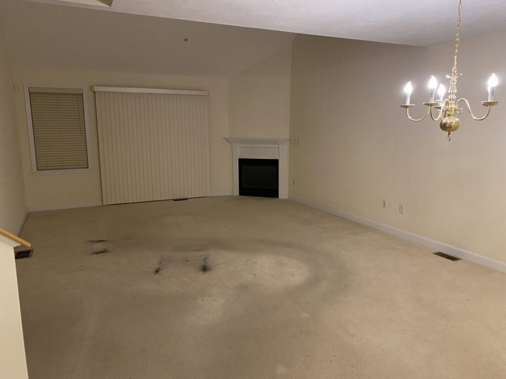 A dirty and stained carpet in a living room before cleaning by Fiber Care Solutions in Whitinsville, MA.