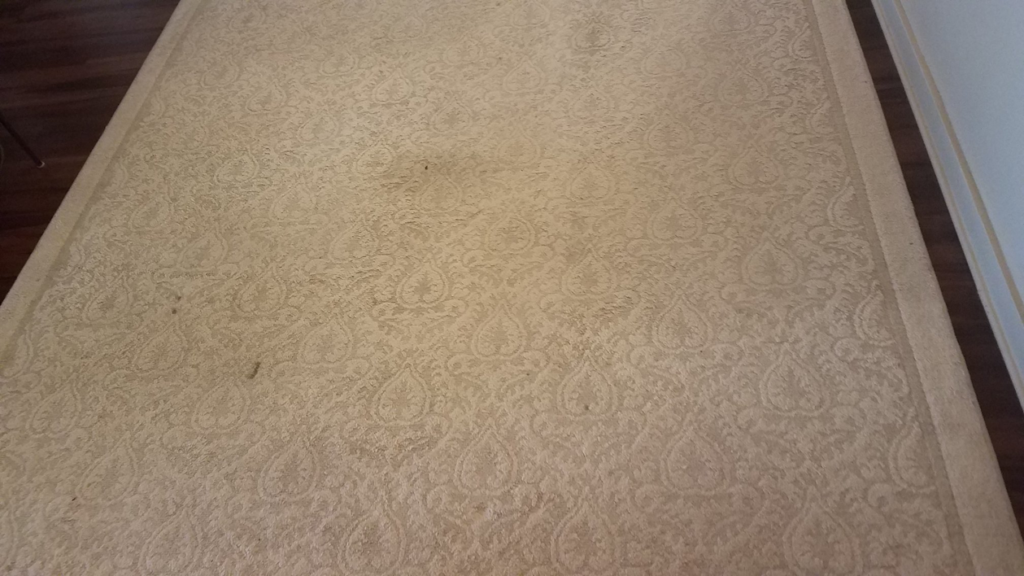 A dirty and stained patterned area rug, showing a 'before' scenario for Haine Floor Care in Honolulu, HI