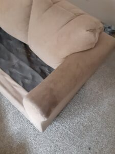 A dirty upholstered sofa armrest showing stains before cleaning by Tex A Clean Carpet Care in League City, TX.