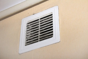 A close-up of a dirty wall-mounted air vent grille, showing dust accumulation, serviced by Murray's General Services in Goose Creek, SC.