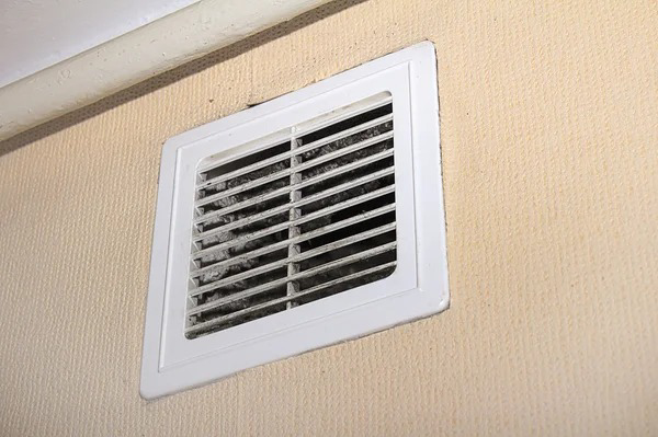 A close-up of a dirty wall-mounted air vent grille, showing dust accumulation, serviced by Murray's General Services in Goose Creek, SC.