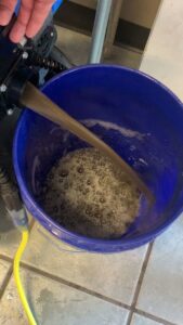 Dirty water being extracted into a blue bucket, demonstrating effective carpet and upholstery cleaning by Good Guys Carpet Cleaning in Katy, TX.