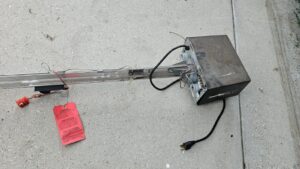 A disassembled Genie garage door opener lying on the ground, indicating a repair or replacement job by BSD Garage Door Service in Naperville, IL.
