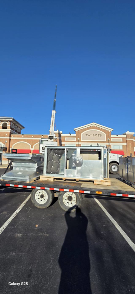 A disassembled commercial HVAC unit on a flatbed trailer with a crane in the background for Cordells Heating and Cooling in Greenville, SC.