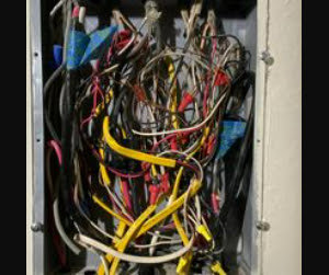 A disorganized electrical panel with numerous wires, indicating a need for service from BR Electric in Newcastle, OK.