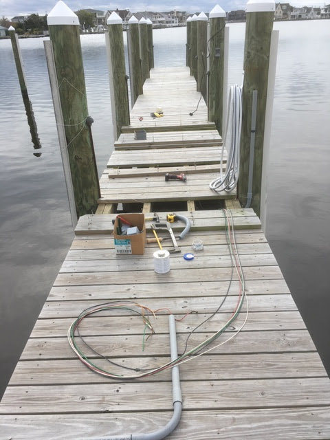 Electrical wiring and conduit laid out on a wooden dock for installation by RTF Electric LLC in Toms River, NJ.