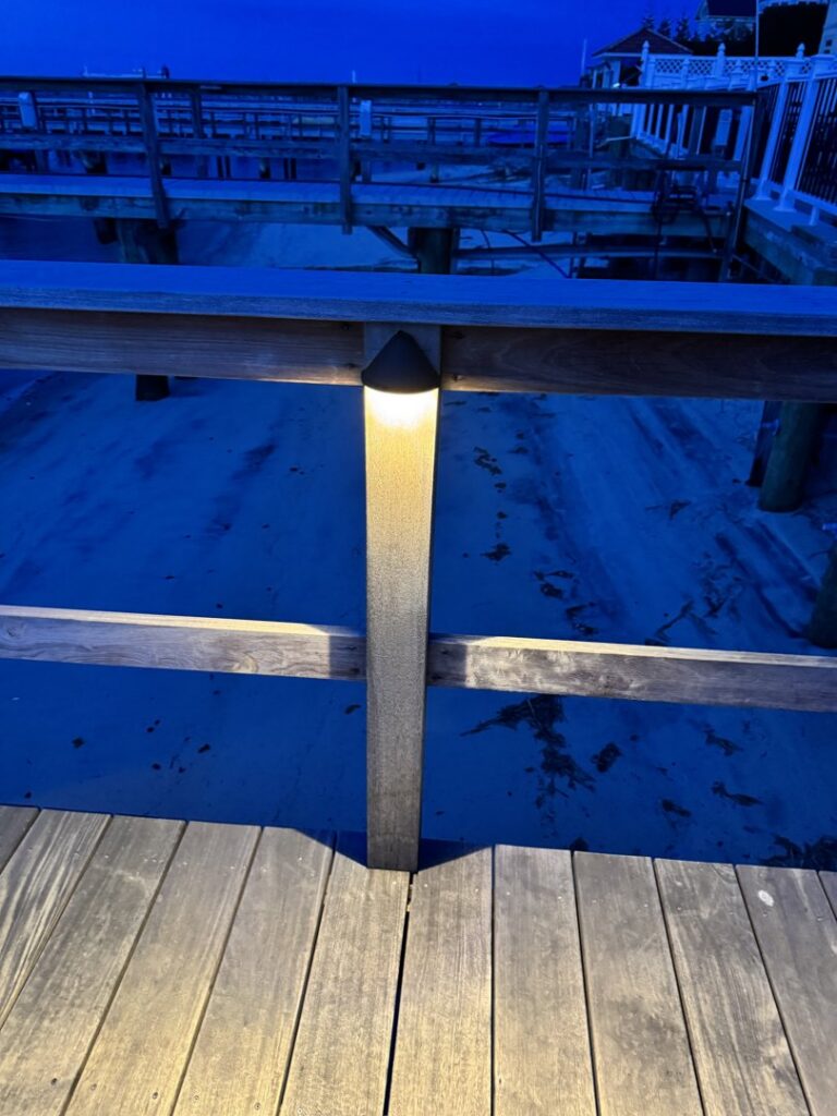 A close-up of a modern post light installed on a wooden dock, showcasing lighting work by New York Electrical Design in Freeport, NY