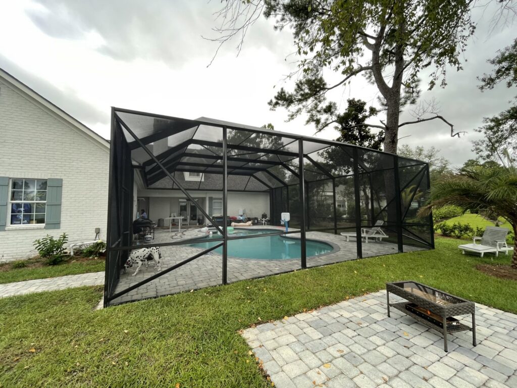 A dog standing by a swimming pool inside a screen enclosure installed by Backyard Paradise in Mobile, AL.