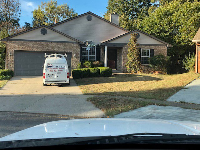 A Door-Tech LLC service van parked in front of a residential home, indicating a job in progress in Lexington, KY.