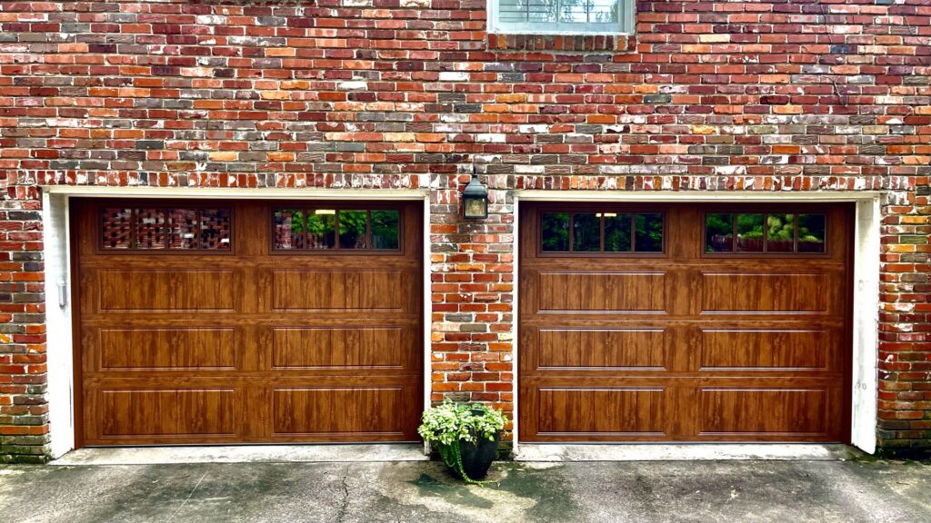 Two elegant brown garage doors with decorative windows installed on a brick house by The Birmingham Man Garage Doors in Birmingham, AL.