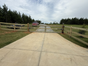 A newly installed double gate with wire mesh and wooden posts at a driveway entrance by G2 Home Solutions in Phenix City, AL.