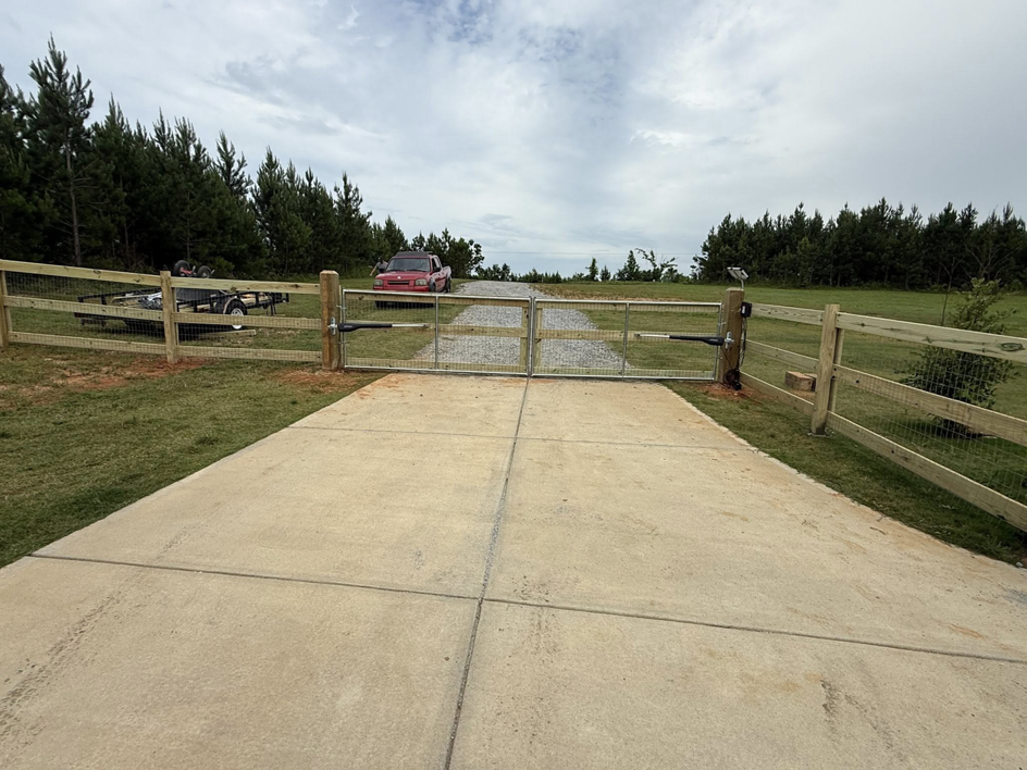 A newly installed double gate with wire mesh and wooden posts at a driveway entrance by G2 Home Solutions in Phenix City, AL.