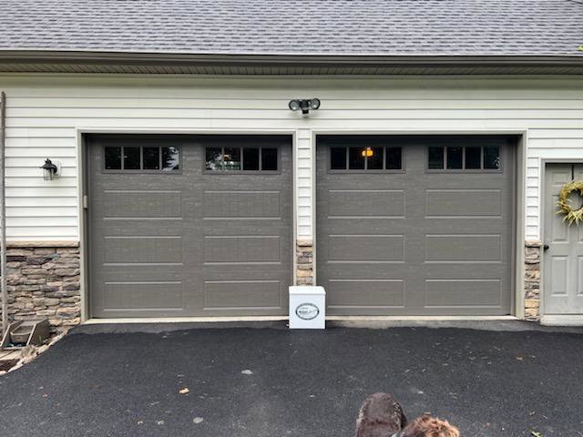 Two newly installed gray garage doors with top windows on a residential home by Door Serv Pro in Inwood, WV.