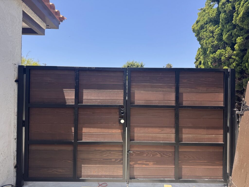 A double gate featuring horizontal wood panels and a sturdy black metal frame, installed by Harwell Fencing & Gates Inc. in Los Angeles, CA.