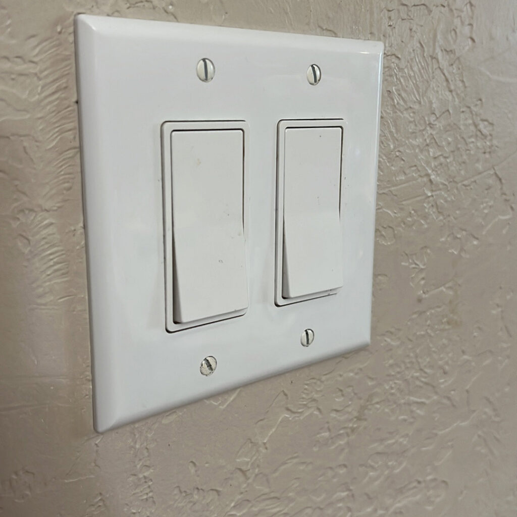 A double light switch installed on a textured wall, showcasing electrical work by Solution Electric in Houston, TX.