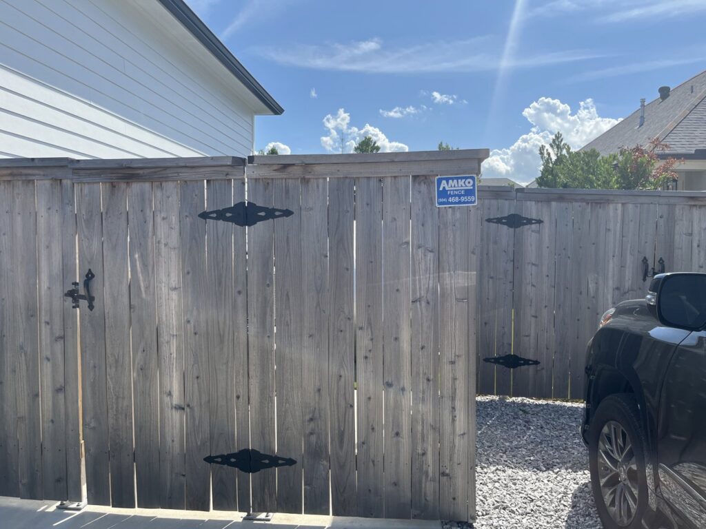 A double wooden gate with decorative black hinges installed by Amko Fence Co. in Kenner, LA.