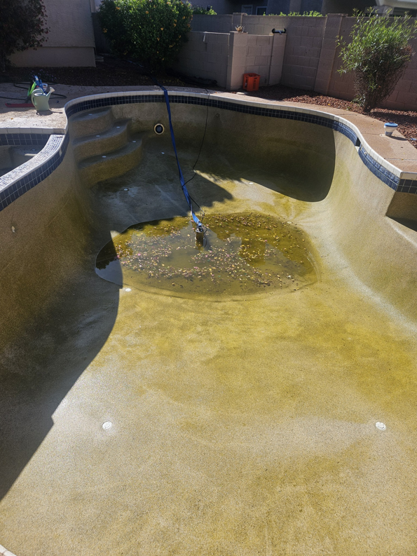 A drained pool with dirty water and debris being removed by Vanguard Pool Care in Phoenix, AZ