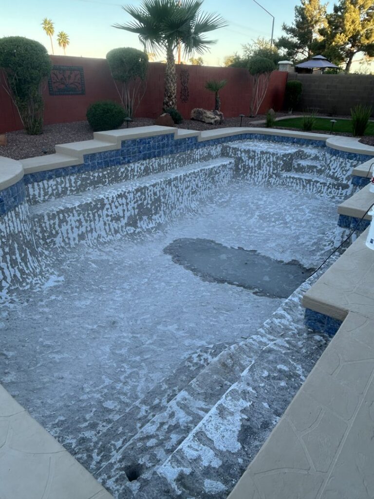 A drained pool with white residue on the bottom and sides, undergoing deep cleaning by E and E Pools in Chandler, AZ.