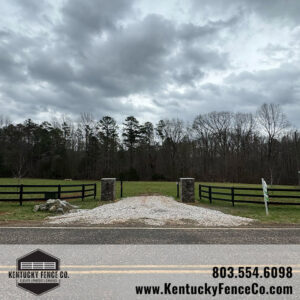 A driveway entrance with stone pillars and black wooden fences installed by Kentucky Fence Co in McConnells, SC.