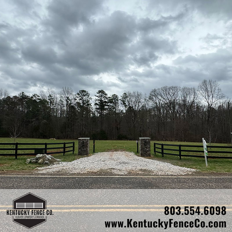 A driveway entrance with stone pillars and black wooden fences installed by Kentucky Fence Co in McConnells, SC.
