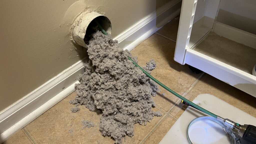 A large amount of lint being extracted from a dryer vent opening during cleaning by Duct Dudes in Scottsdale, AZ.