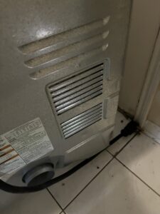 The back of a clothes dryer showing the vent connection, indicating dryer vent cleaning services by AirHero.Pro in Lafayette, LA.