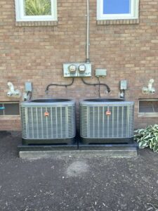 Two outdoor air conditioning units installed side-by-side next to a brick home by My HVAC Guy in North Canton, OH.