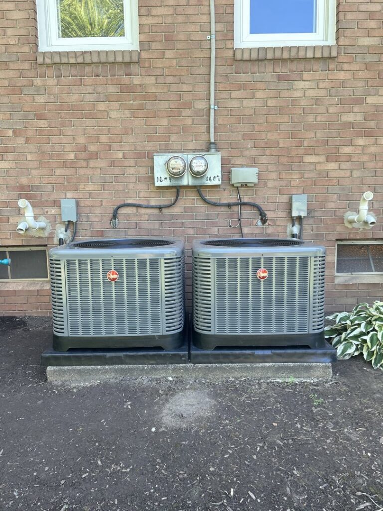 Two outdoor air conditioning units installed side-by-side next to a brick home by My HVAC Guy in North Canton, OH.