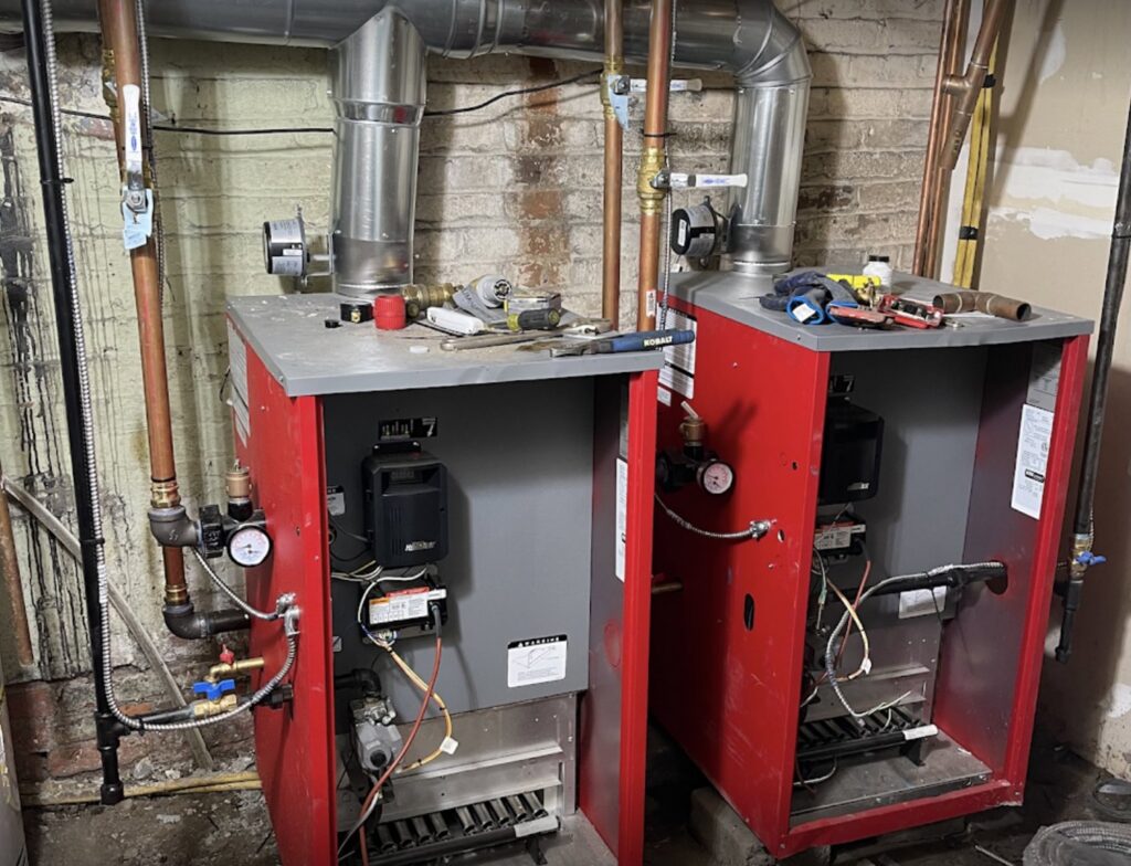 Two red boilers with extensive piping installed by Best Plumbing Heating & Cooling Contractors in Albany, NY.