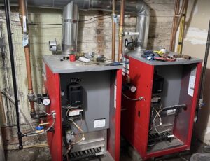 Two red boilers with extensive piping installed by Best Plumbing Heating & Cooling Contractors in Albany, NY.