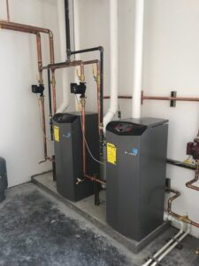 A clean installation of two modern boilers with copper piping for a heating system by Boiler Man Plumbing & Heating in Palmer, AK