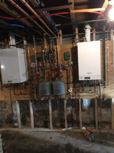 A dual wall-mounted boiler and hot water system installation with extensive copper piping by Nate's Oil Burner Service in New Bedford, MA