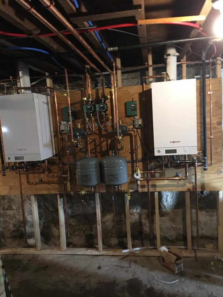 A dual wall-mounted boiler and hot water system installation with extensive copper piping by Nate's Oil Burner Service in New Bedford, MA
