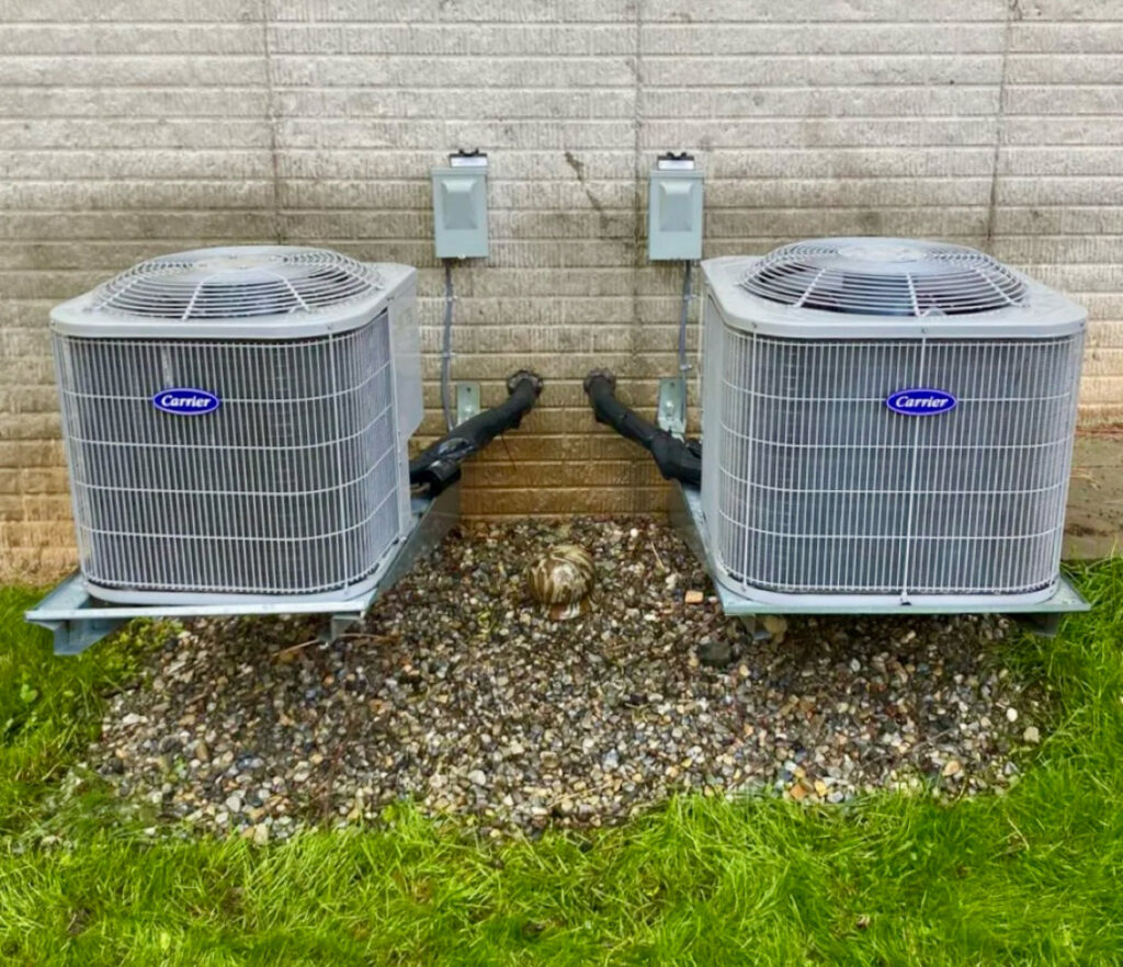Two Carrier outdoor AC condenser units installed on wall mounts by Infinite Heating & Air in Newnan, GA.